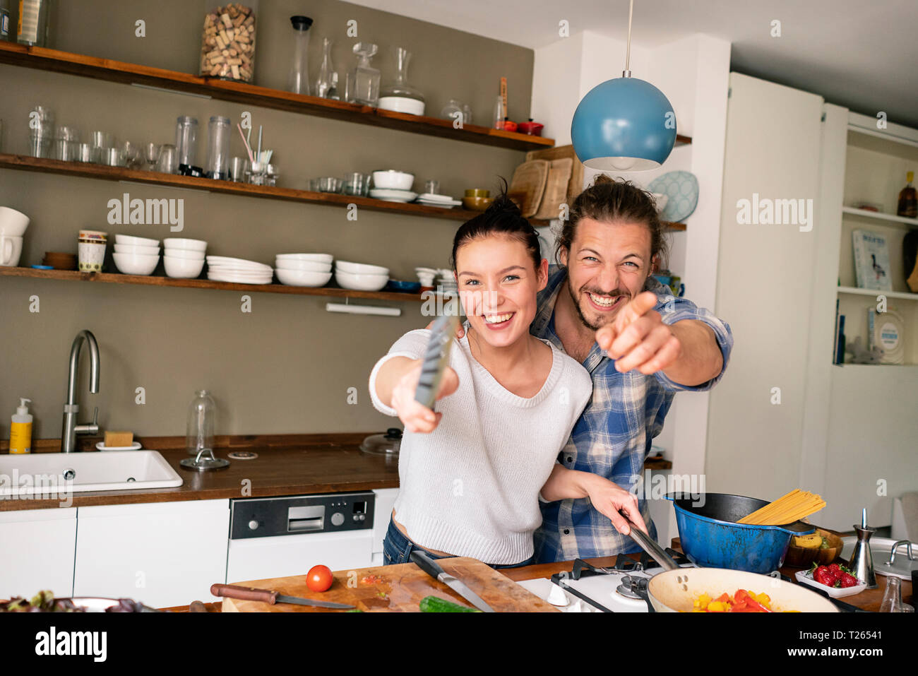 Junges Paar essen zusammen vorbereiten, Lachen und zeigte mit Spachtel Stockfoto