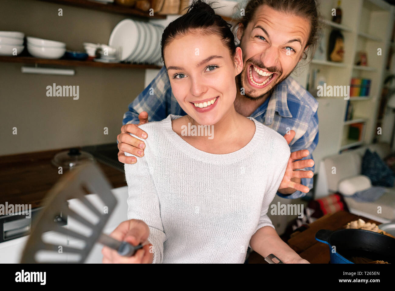 Junges Paar essen zusammen vorbereiten, Lachen und zeigte mit Spachtel Stockfoto