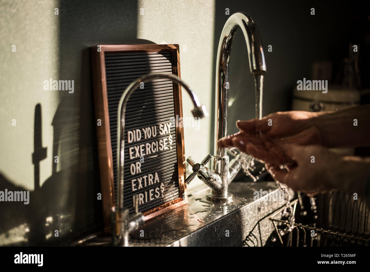 Vorstand mit lustigen Text an der Spüle, wo ein Mann seine Hände waschen Stockfoto