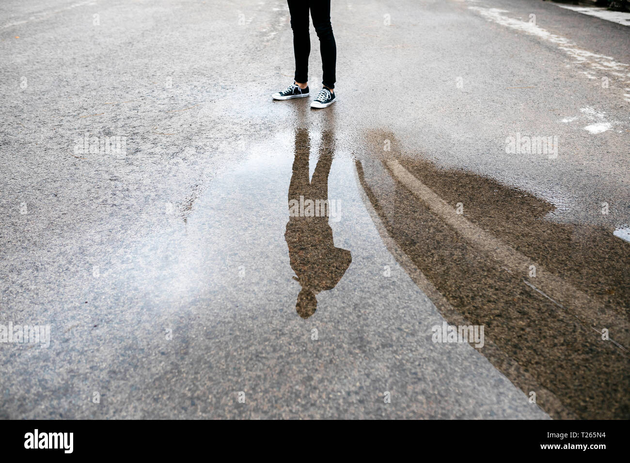 Reflektion von einem Mann in einer Pfütze auf dem Boden Stockfoto