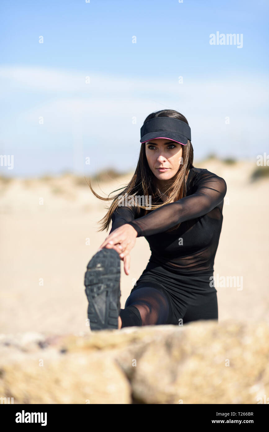 Sportliche Frau ihr Bein stretching auf stein Wand Stockfoto