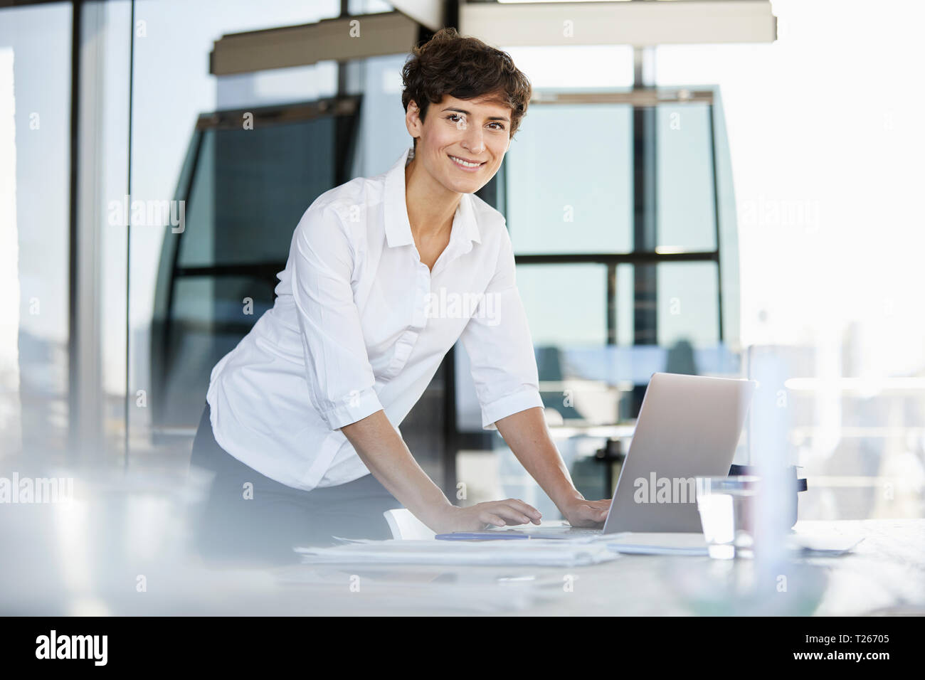 Portrait von zuversichtlich Geschäftsfrau am Schreibtisch im Büro mit Laptops Stockfoto