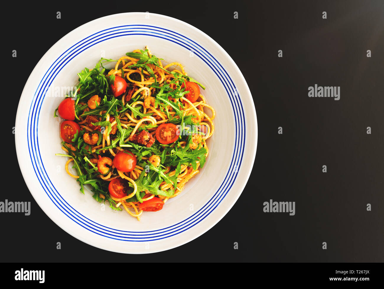 Pasta Teller mit Spaghetti mit Garnelen, Rucola und getrockneten eine frische Tomaten Stockfoto