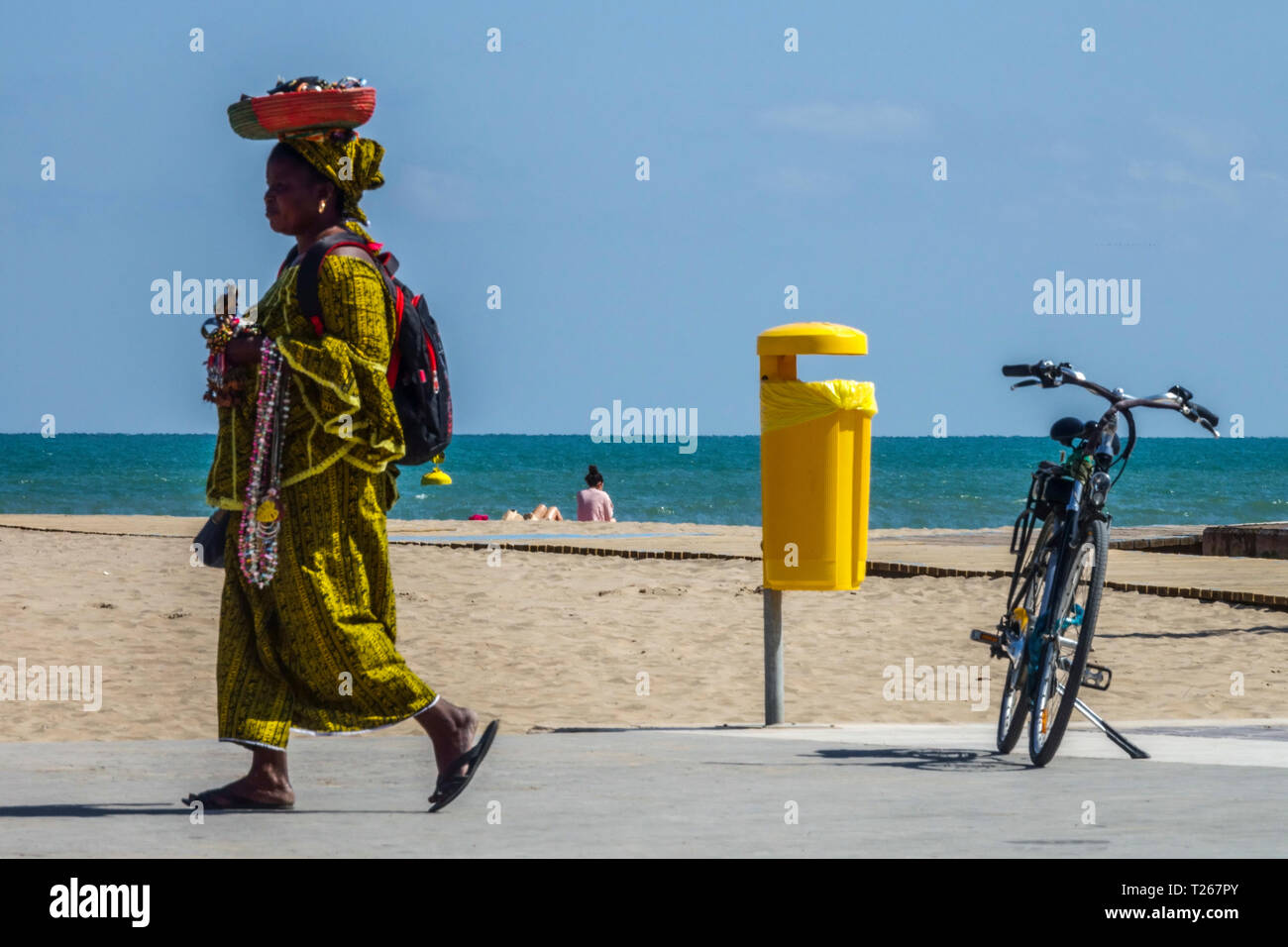Afrikanische Frau in traditioneller Kleidung verkaufen kleine Schmuck am Strand Malvarrosa, Valencia, Spanien Stockfoto