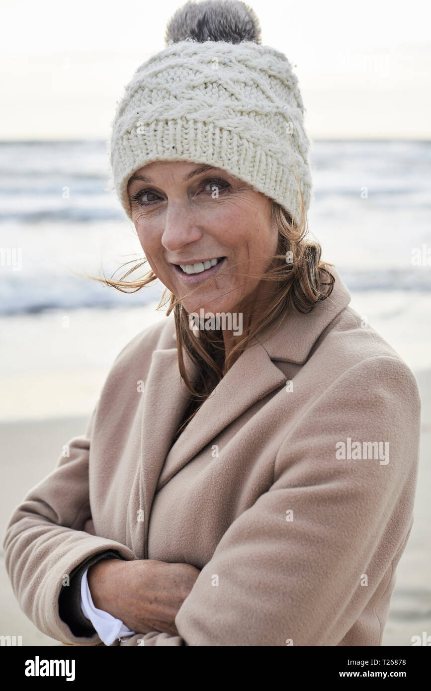 Spanien, Menorca, Portrait von lächelnden älteren Frau bobble Hut auf dem Strand im Winter Stockfoto