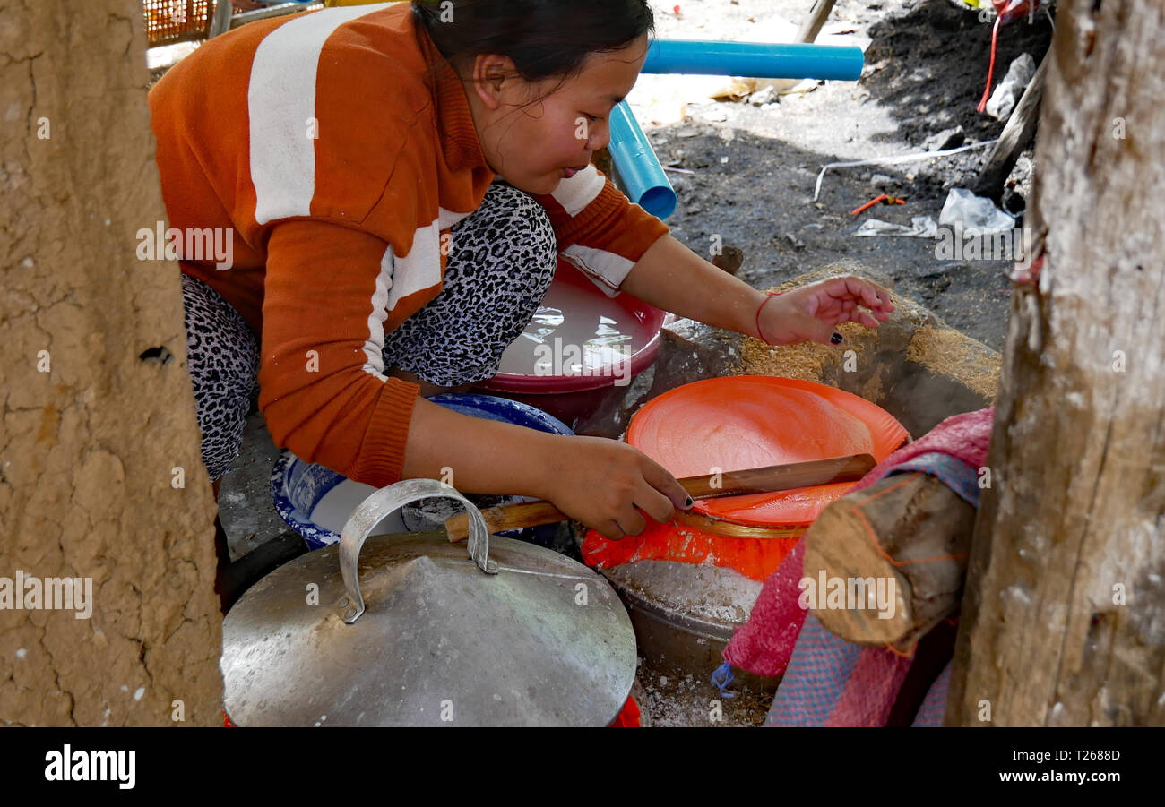 In Battambang, Kambodscha. Eine Frau nimmt vorsichtig nach einem nassen und zarte Blatt reispapier von der Oberfläche von der Dampfeinheit. 10-12-2018 Stockfoto