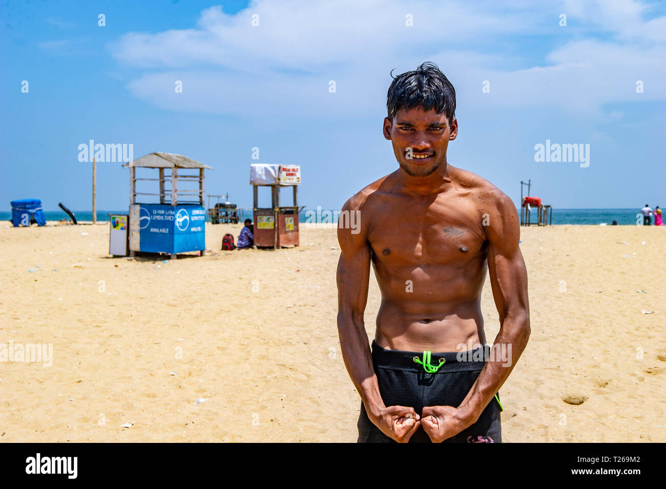 Ein junger Inder biegt sich seine Muskeln im Marina Beach, Golf von Bengalen in Chennai, Indien Stockfoto