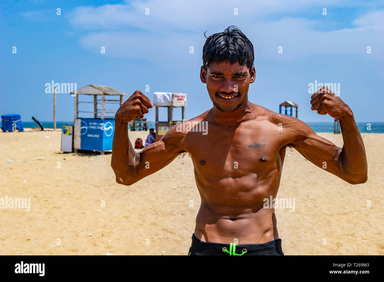 Ein junger Inder biegt sich seine Muskeln im Marina Beach, Golf von Bengalen in Chennai, Indien Stockfoto