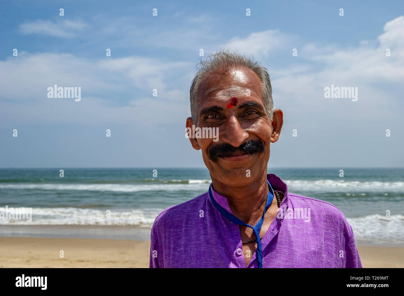 Ein Schnurrbärtige, lächelnd Gentleman mit einem Bindi genießt das Meer bei Marina Beach, in der Bucht von Bengalen in Chennai, Indien Stockfoto