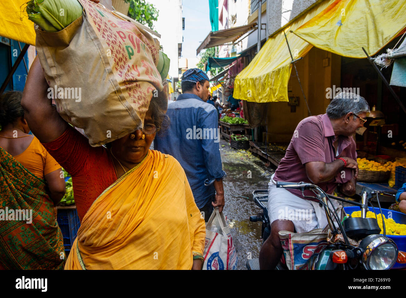 Der Händler trägt große Mengen von Lebensmitteln auf ihren Kopf in George Town Market, Chennai, Indien Stockfoto