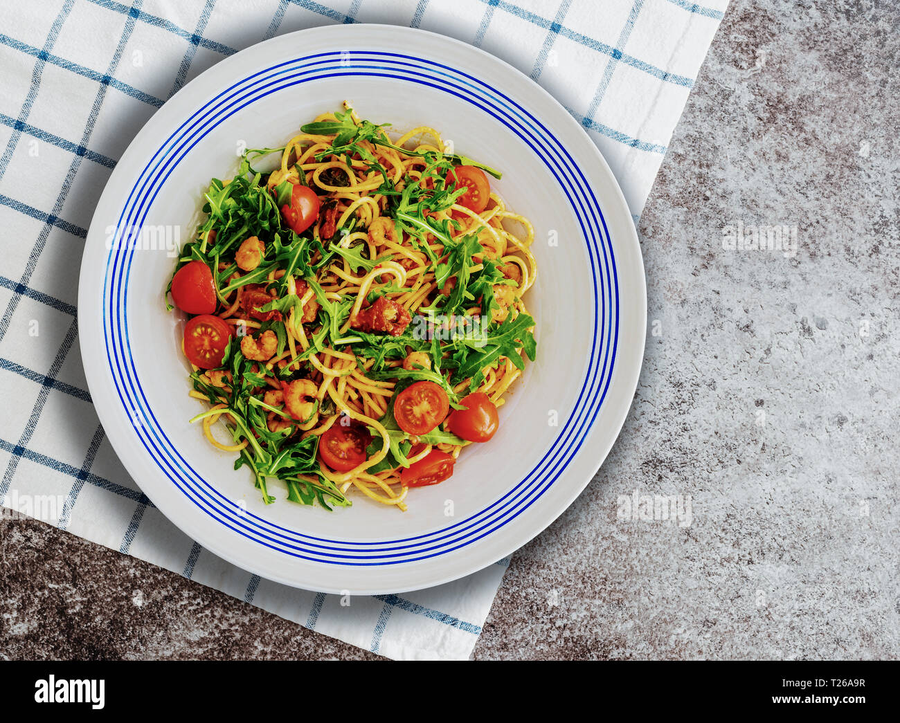 Pasta Teller mit Spaghetti mit Garnelen, Rucola und getrockneten und frischen Tomaten Stockfoto