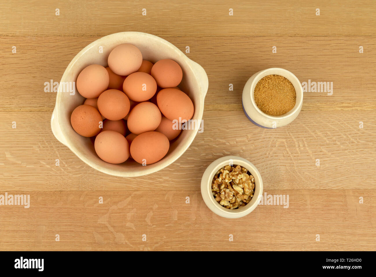 Arm frische organische Eier aus Freilandhaltung, Walnüsse und braunen Zucker in Schalen. Ansicht von oben. Bauernhof bis auf den Tisch Stockfoto
