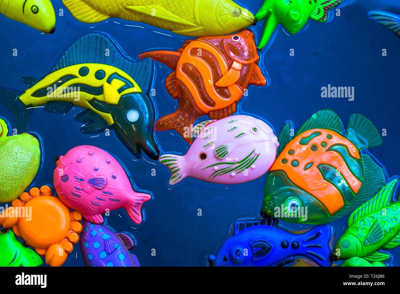 Mehrere igushek in Form von marine Fische schwimmen im Wasser. Die Spielzeuge sind sehr helle Farben und schönen vor dem Hintergrund des blauen Wassers. Stockfoto