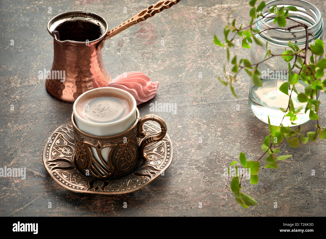 Orientalischen Kaffee in traditionellen Türkischen zubereitet wird gegossen in einer Schale auf einem dunklen Tabelle Stockfoto