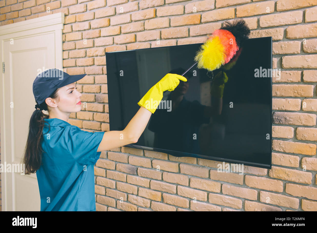 Ein Bild des Mädchens Reinigung TV aus dem Staub. Sie ues Staub putzen. Es ist bunt. Mädchen arbeitet mit Vergnügen Stockfoto