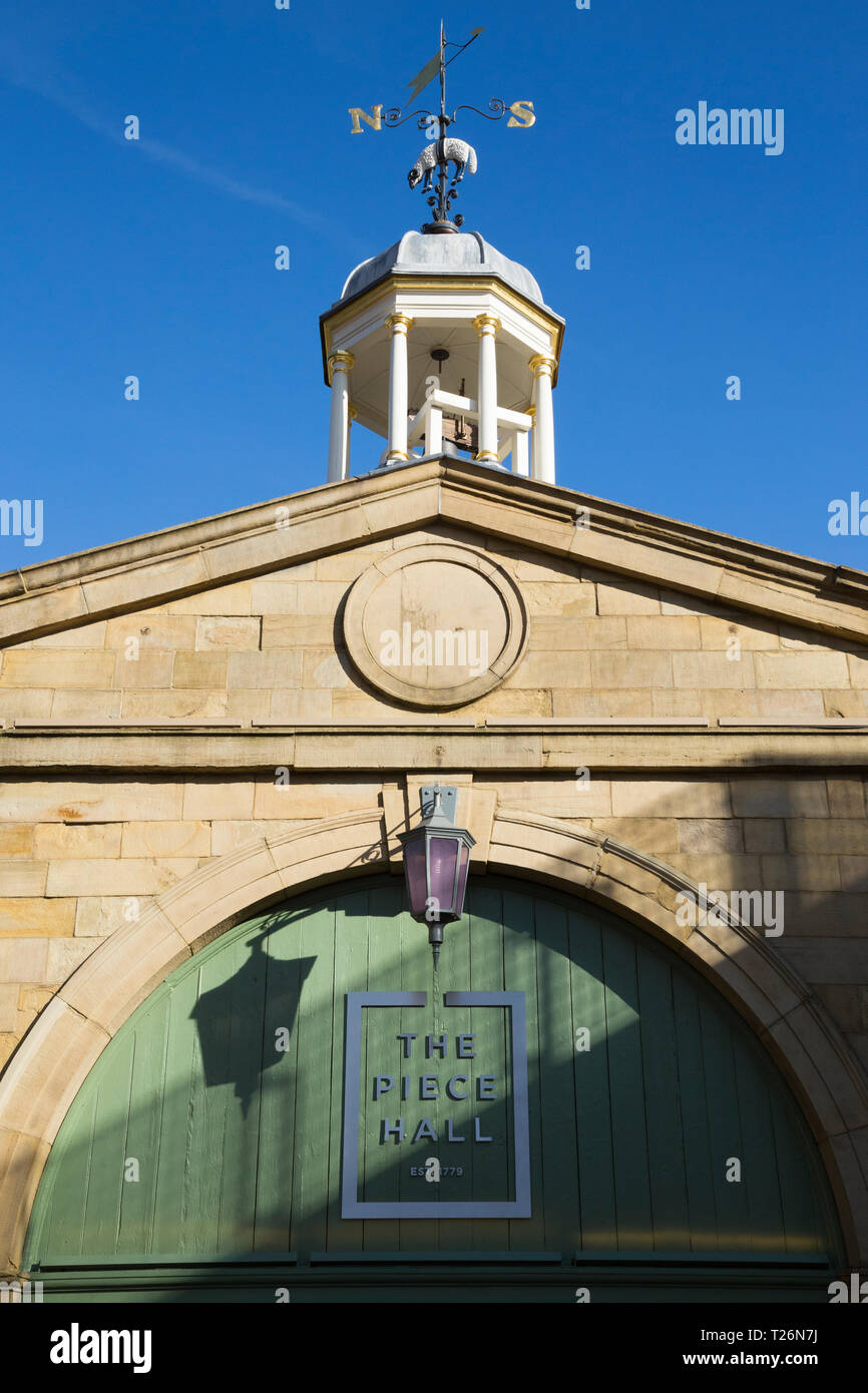 Tor in der Westwand, Eingang von Westgate, in das Stück Halle. Piece Hall Logo angezeigt wird. Sonnig / Sonne und blauen Himmel. Halifax, West Yorkshire, UK Stockfoto