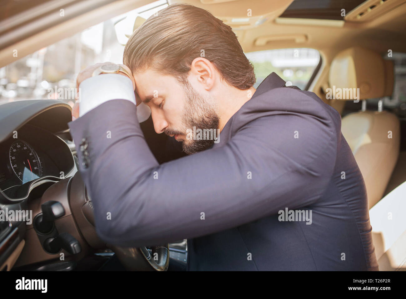 Müde und erschöpft junge Geschäftsmann auf dem Auto sitzt und lehnt sich an das Lenkrad. Er hält die Augen geschlossen. Junger Mann schlafen Stockfoto