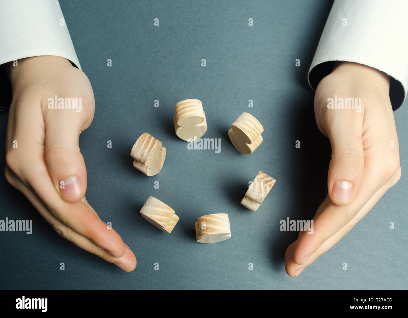 Ein Mann wickelt seine Arme um einen Kreis von menschlichen Figuren. Zusammenarbeit und Einheit, Teamarbeit, Versicherungs- und Personalmanagement. Führung, Kontrolle über die Stockfoto