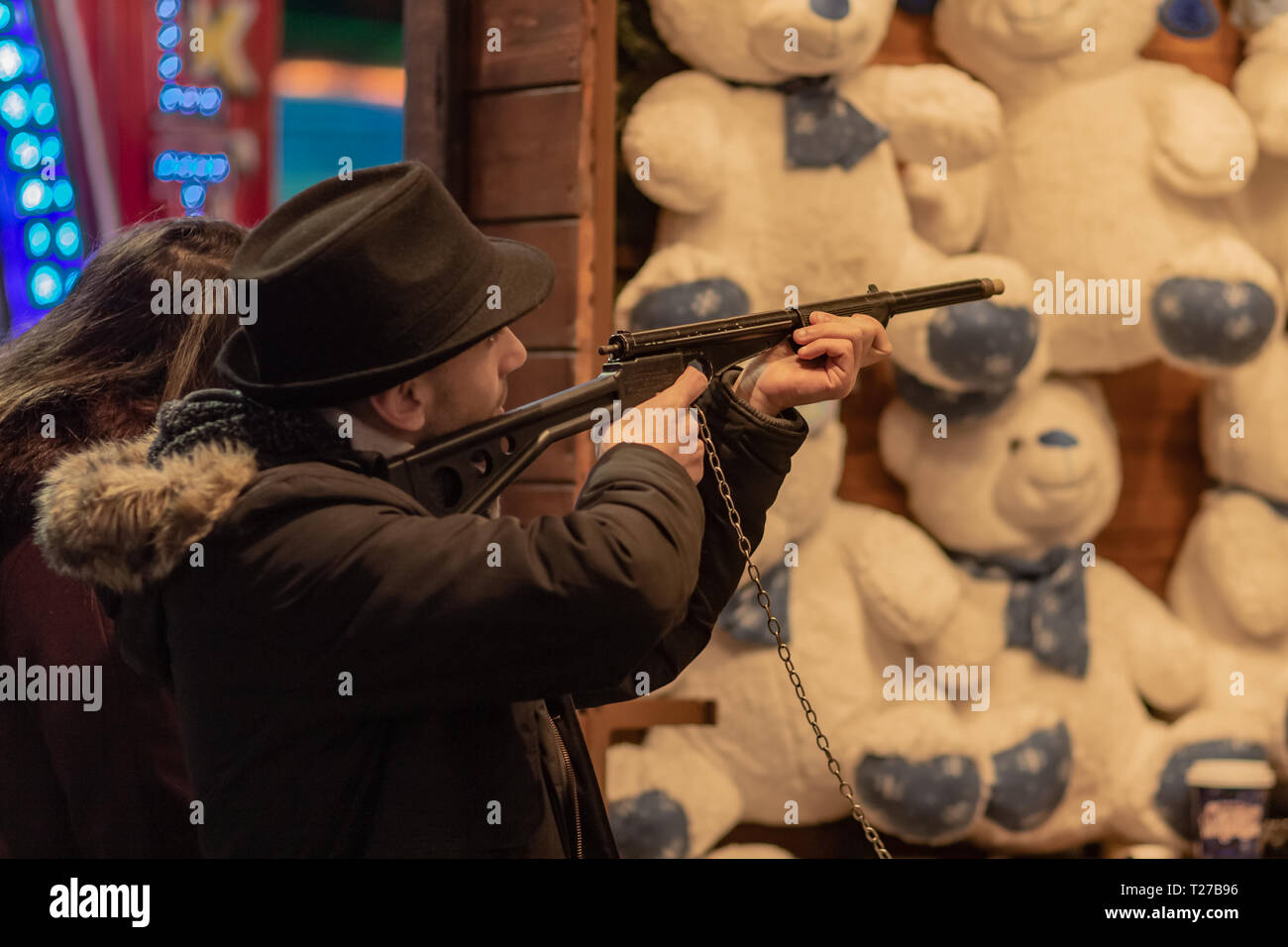 London, Großbritannien - 17, Dezember 2018: Amusement Park bei Nacht - Mann mit Gewehr schießen tragen Stockfoto