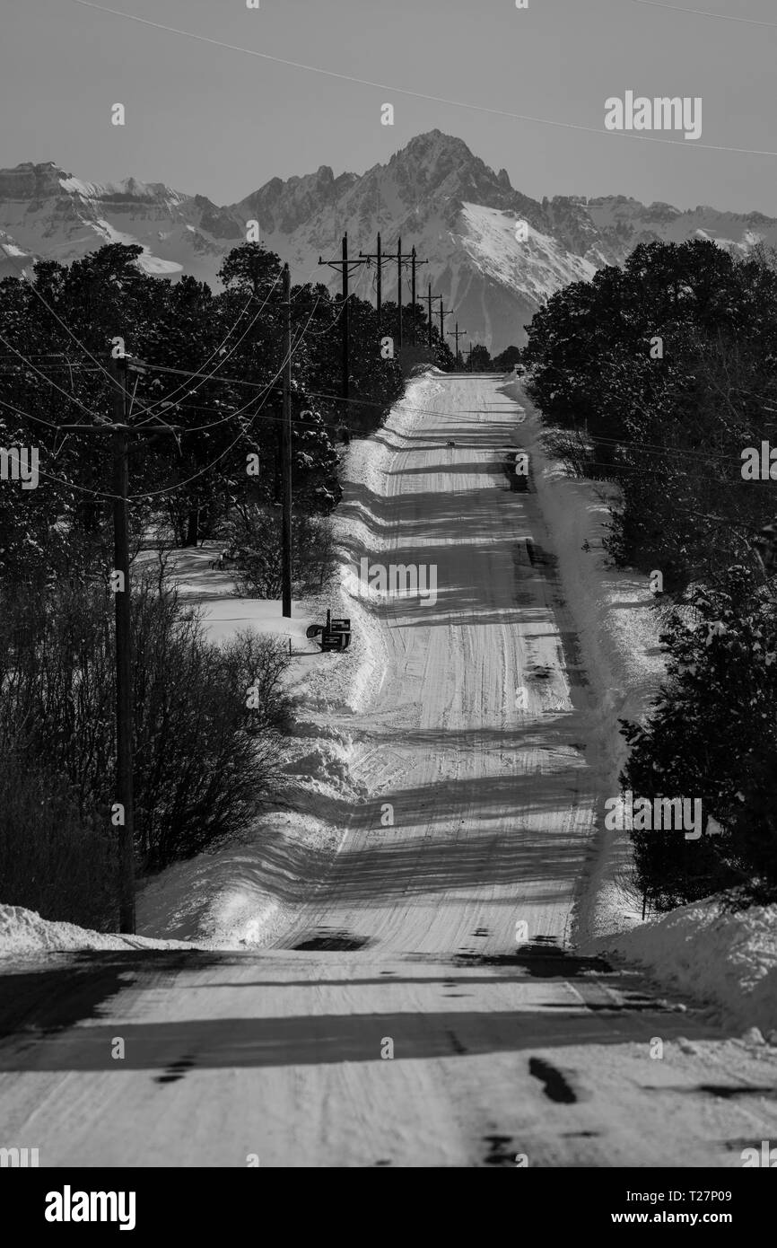 Februar 24, 2019 - RIDGWAY COLORADO USA - Winter verschneite Straße durch tiefen Schnee führt zu San Juan Berge schleppt Lauffläche der Reifen verlassen Stockfoto