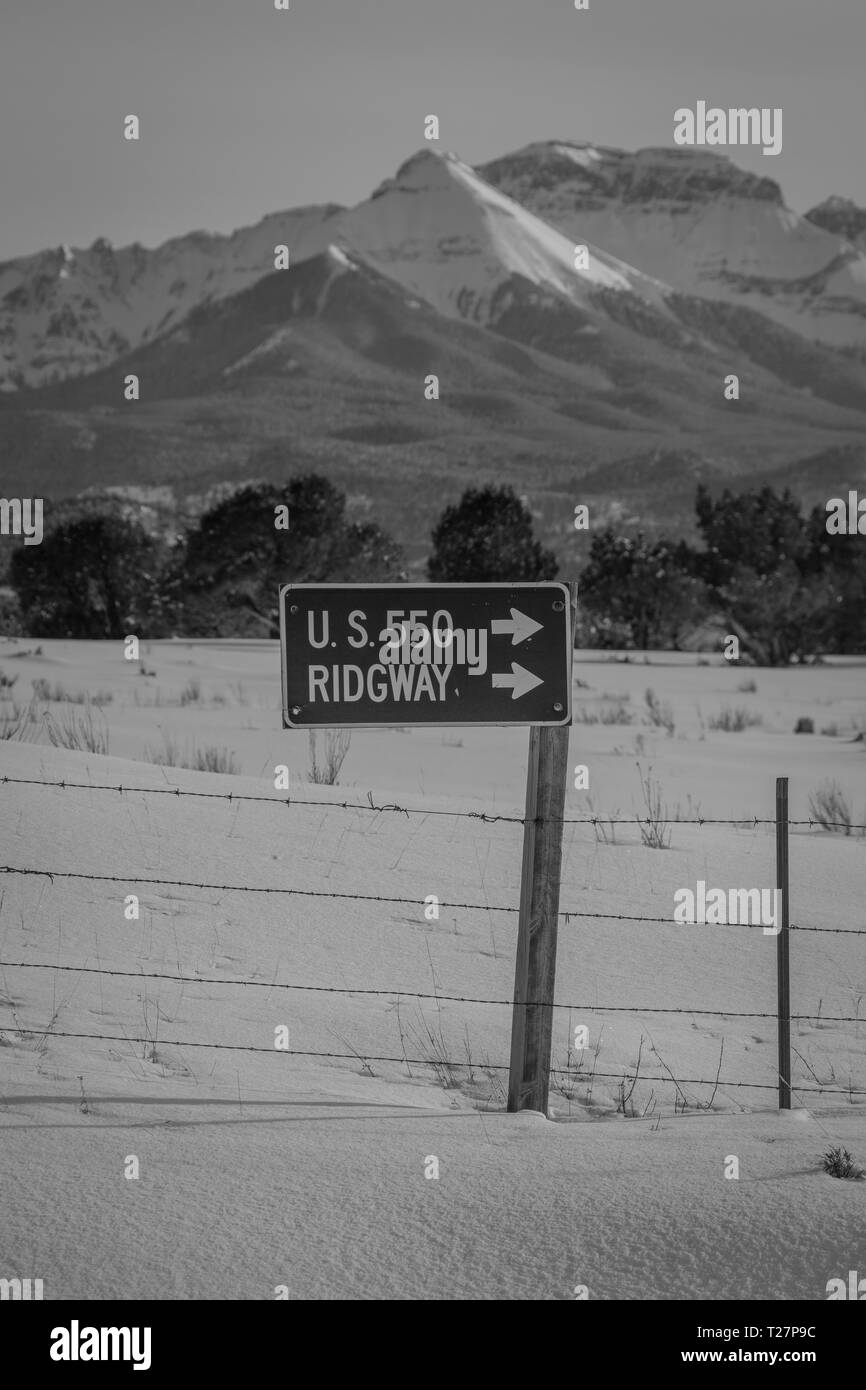 Februar 27, 2019 - RIDGWAY, Colorado, USA - Winter Schnee Schild weist auf Ridgway und Colorado State Route 550 mit San Juan Berge im Hintergrund Stockfoto