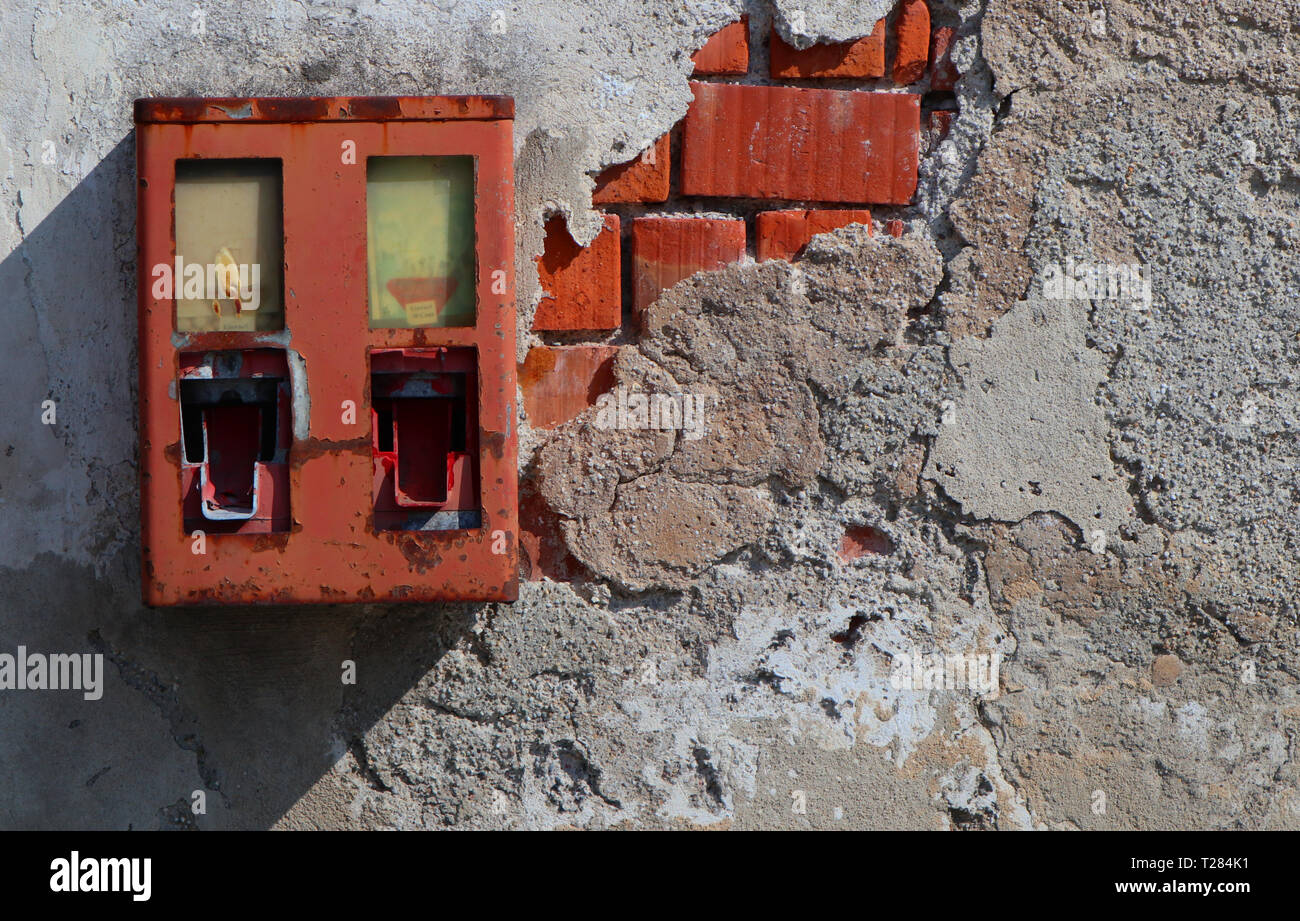 Alte vernachlässigt gumball Machine auf einem heruntergekommenen Haus Wand Stockfoto