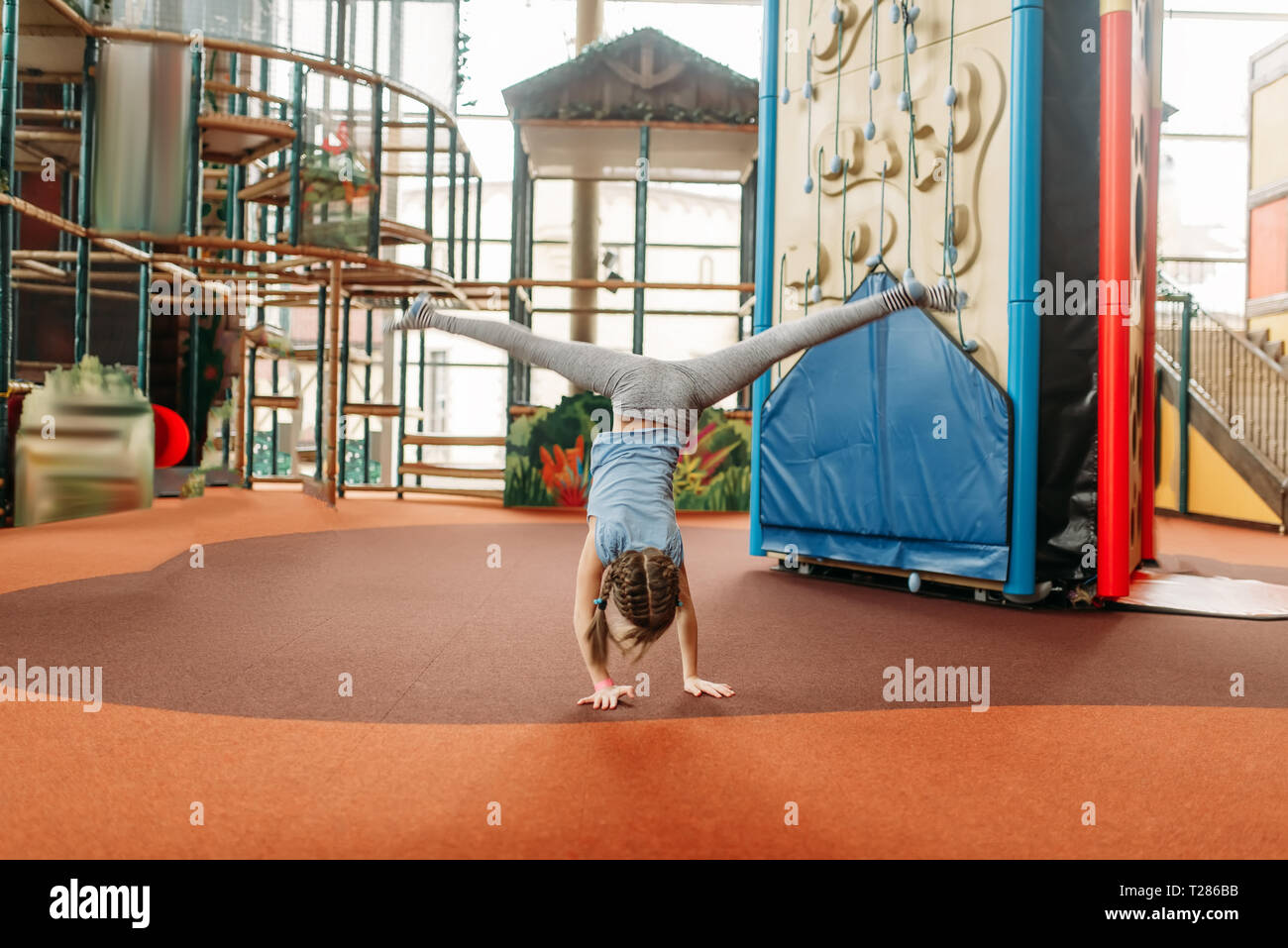 Lustig Mädchen stehen auf ihre Hände auf den Kopf bei Kindern Game Center. Aufgeregt haben Kinder Spaß auf dem Spielplatz im Freien. Weibliche Kid spielen in den Vergnügungspark Stockfoto