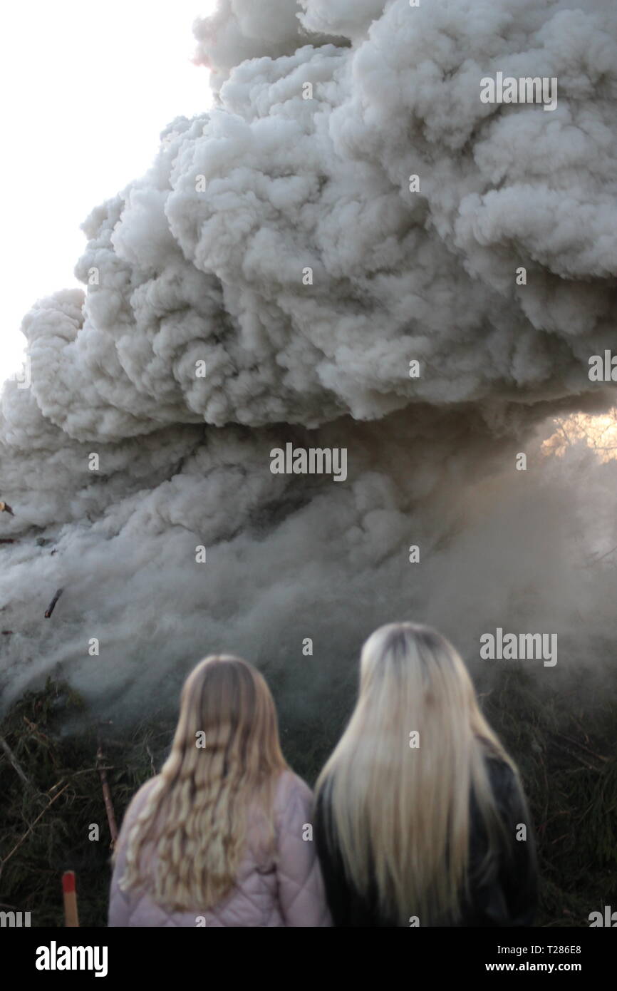 Zwei Mädchen wathing zu einem Brand mit starker Rauchentwicklung. Feiern des Valborgsmässoafton in Schweden. Schwedische Tradition. Stockfoto