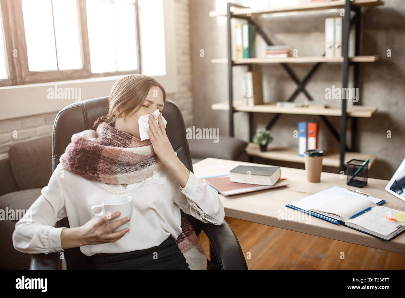 Kranke junge geschäftsfrau am Tisch im Zimmer sitzen und Niesen. Sie leiden an der Krankheit. Frau kann nicht arbeiten. Stockfoto