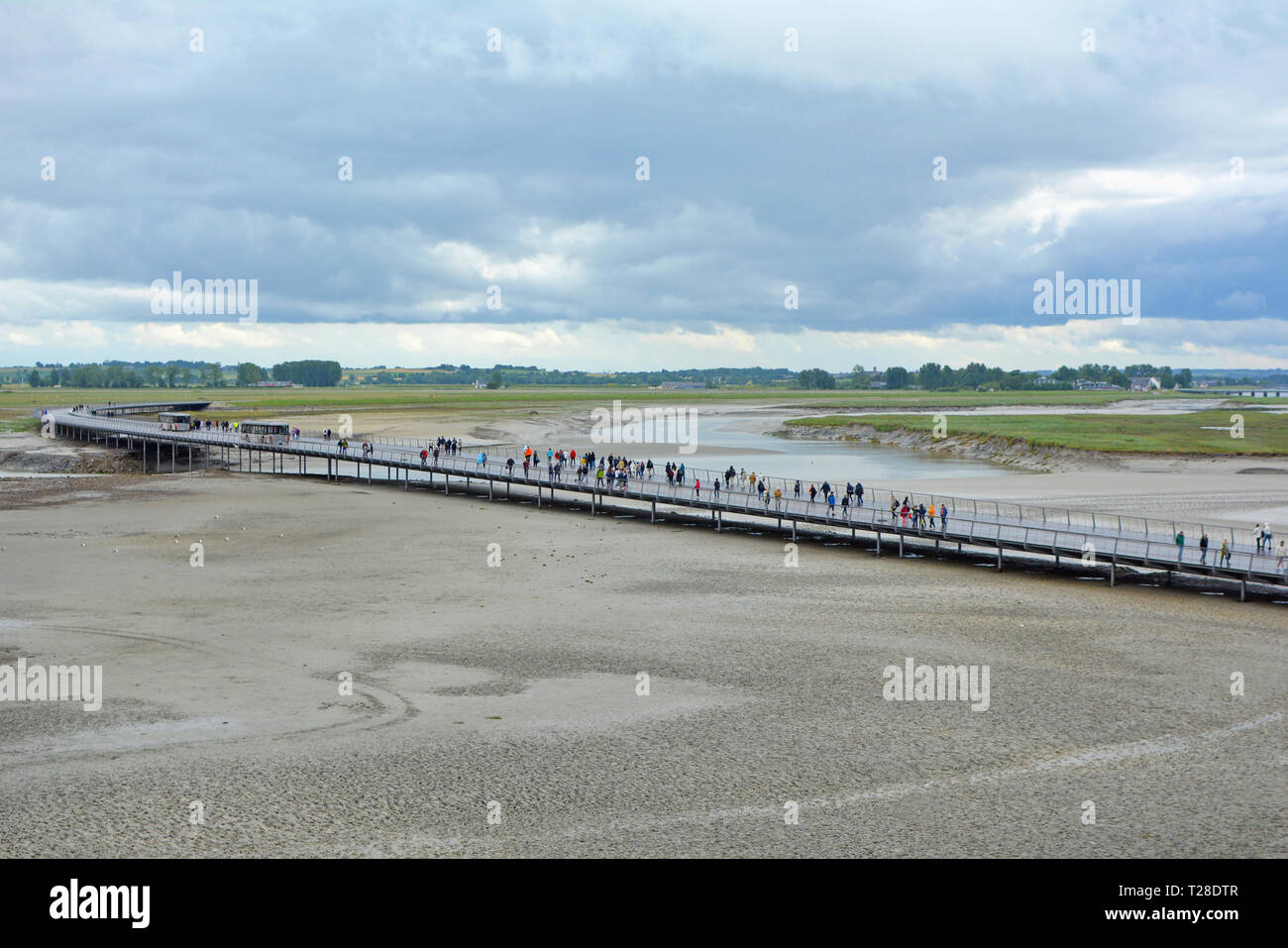 Brücke mit Touristen, die zu französischen historische Sehenswürdigkeiten attracktion Le Mont Saint Michel über das Wasser bei Ebbe an einem regnerischen Tag Stockfoto