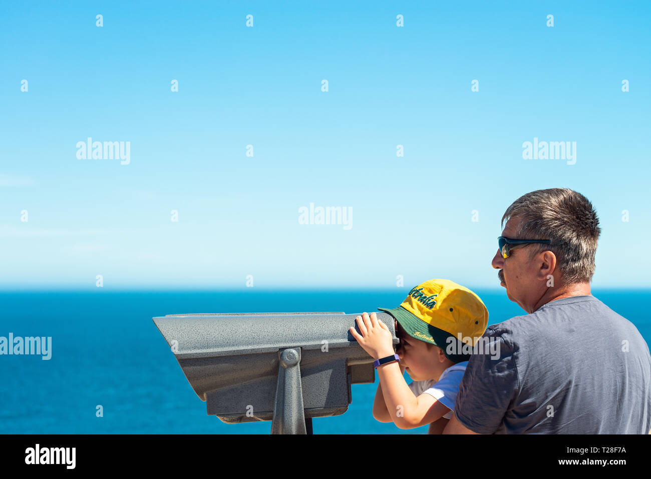 Großvater und Enkel beobachten Känguruh Insel Küste Landschaft durch outdoor Fernglas von Cape Jervis, South Australia. Stockfoto