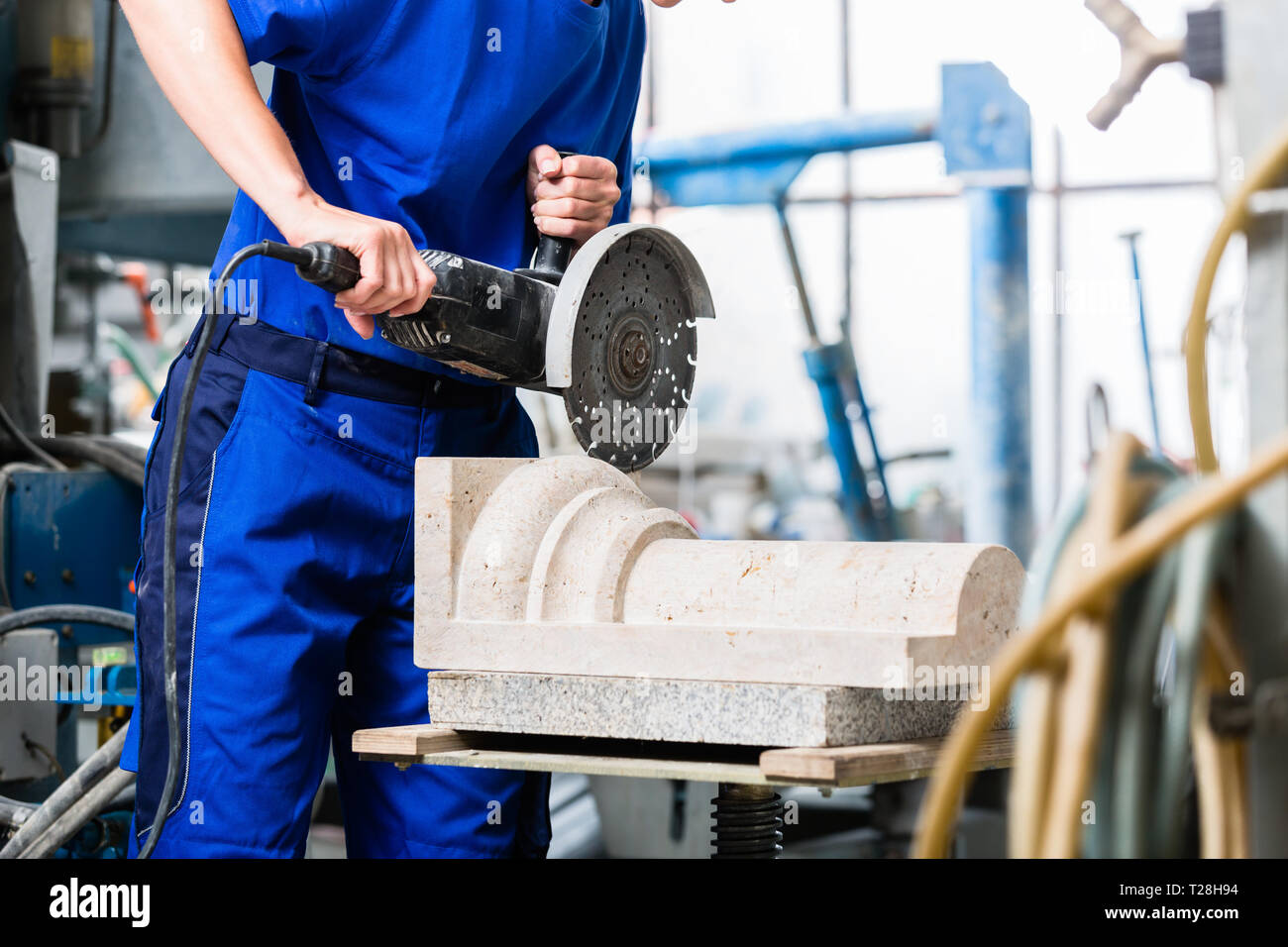 Weibliche Bildhauer Schneiden von Stein mit dem Winkelschleifer Stockfoto