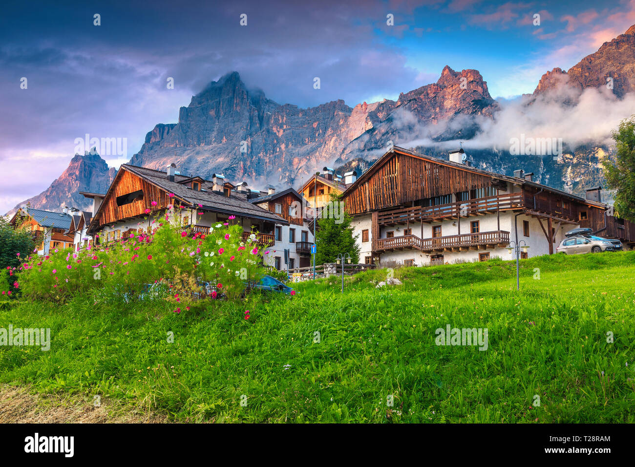 Berühmte Alpine Village bei Sonnenuntergang. Wunderschöne traditionelle Häuser und herrlichen Gärten. Hohe Berge bei Sonnenuntergang in San Vito di Cadore, Dolomiten, Stockfoto