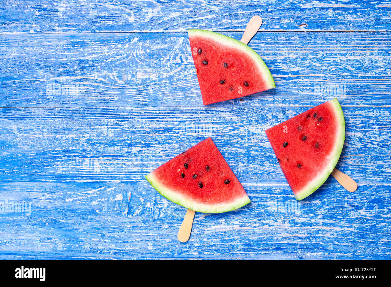 Scheibe frische Wassermelone auf einem Stock. Wassermelone ist in der Form eines Dreiecks schneiden. auf blauem Hintergrund Holz Stockfoto