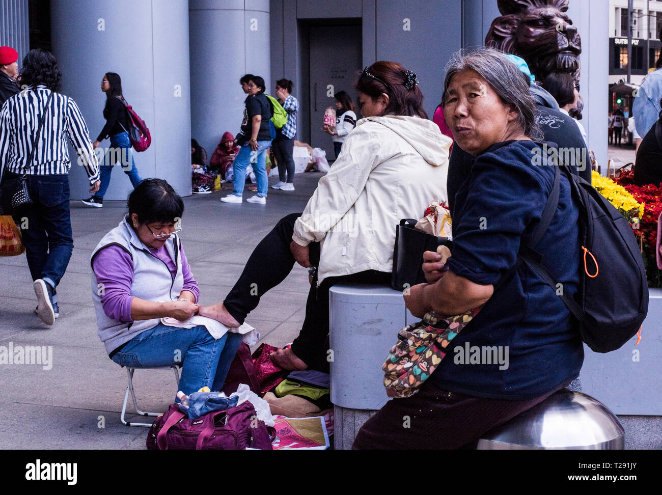 Frau mit Pediküre in verkehrsreichen Straße, ältere Frau im Vordergrund Blick auf Kamera, Kowloon, Hong Kong Stockfoto
