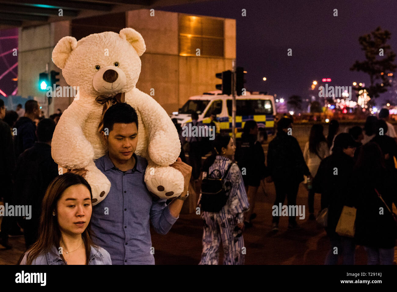 Mann, der riesige Teddybären auf den Schultern, und die Straße mit Menschen gefüllt, während das chinesische Neujahr feiern, Kowloon, Hong Kong Stockfoto