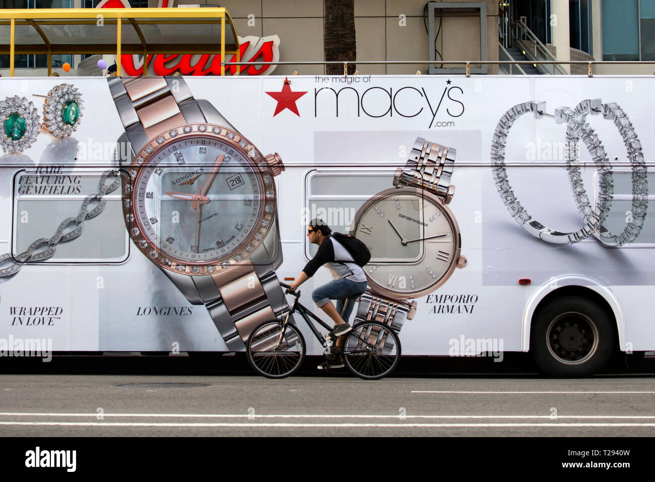 LOS ANGELES - Radfahrer vor einem tourbus Werbung Macy's Schmuck und Uhren auf dem Hollywood Boulevard. Stockfoto