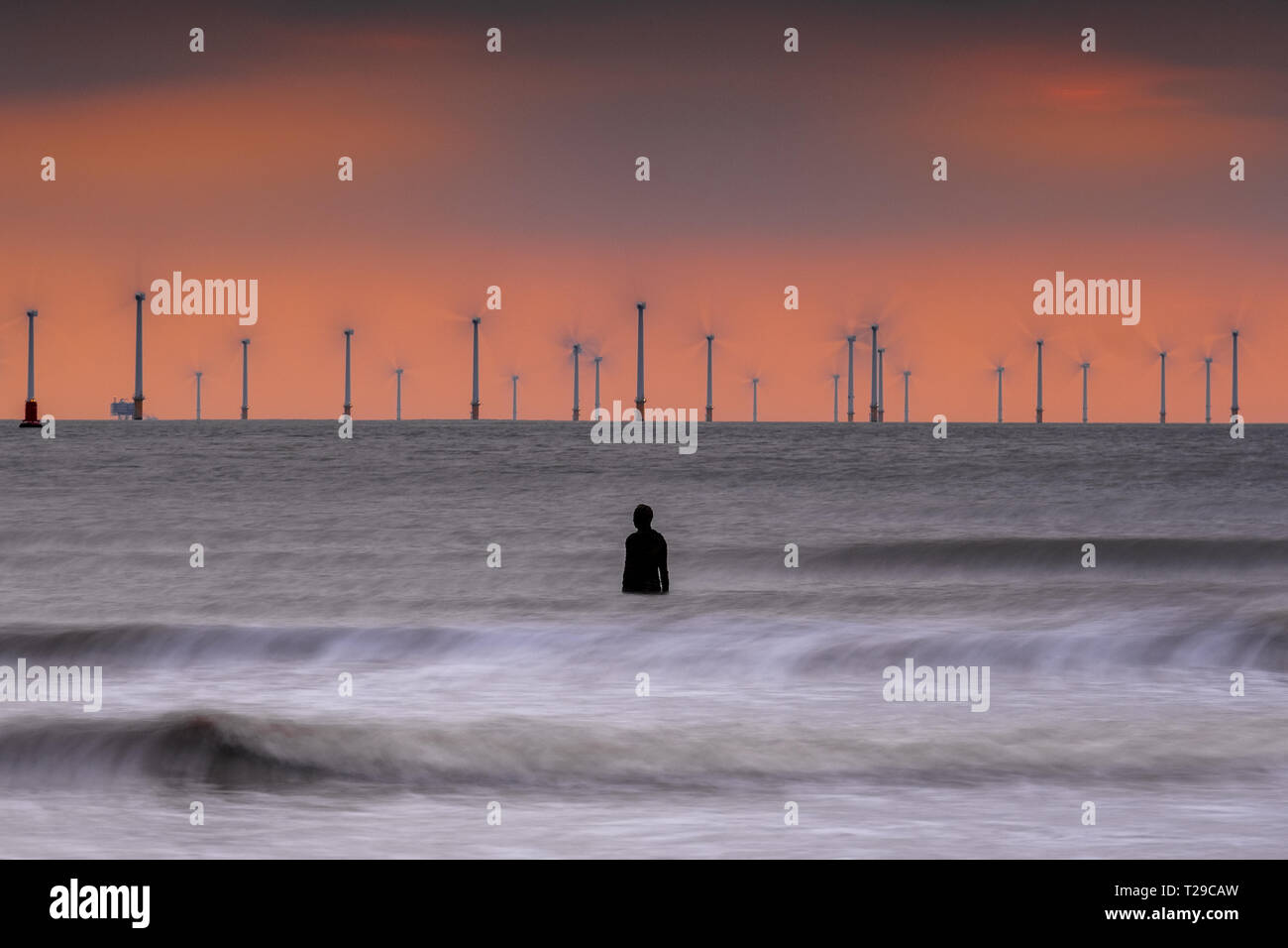 Crosby Strand, UK. März 31, 2019: Crosby, UK. Die Sonne als Wellen um eine von Gusseisen Antony Gormley Statuen auf Crosby Strand an der Sefton Coast abstürzen. Quelle: Christopher Middleton/Alamy leben Nachrichten Stockfoto