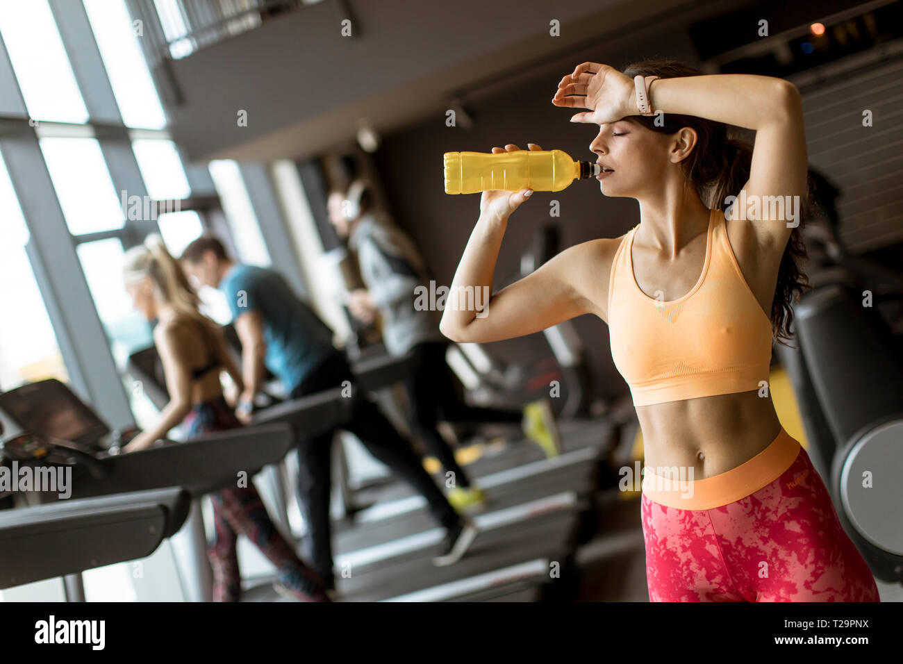 Gesunde Frauen in gelb Sport Shirt sind Trinkwasser an der Turnhalle Stockfoto