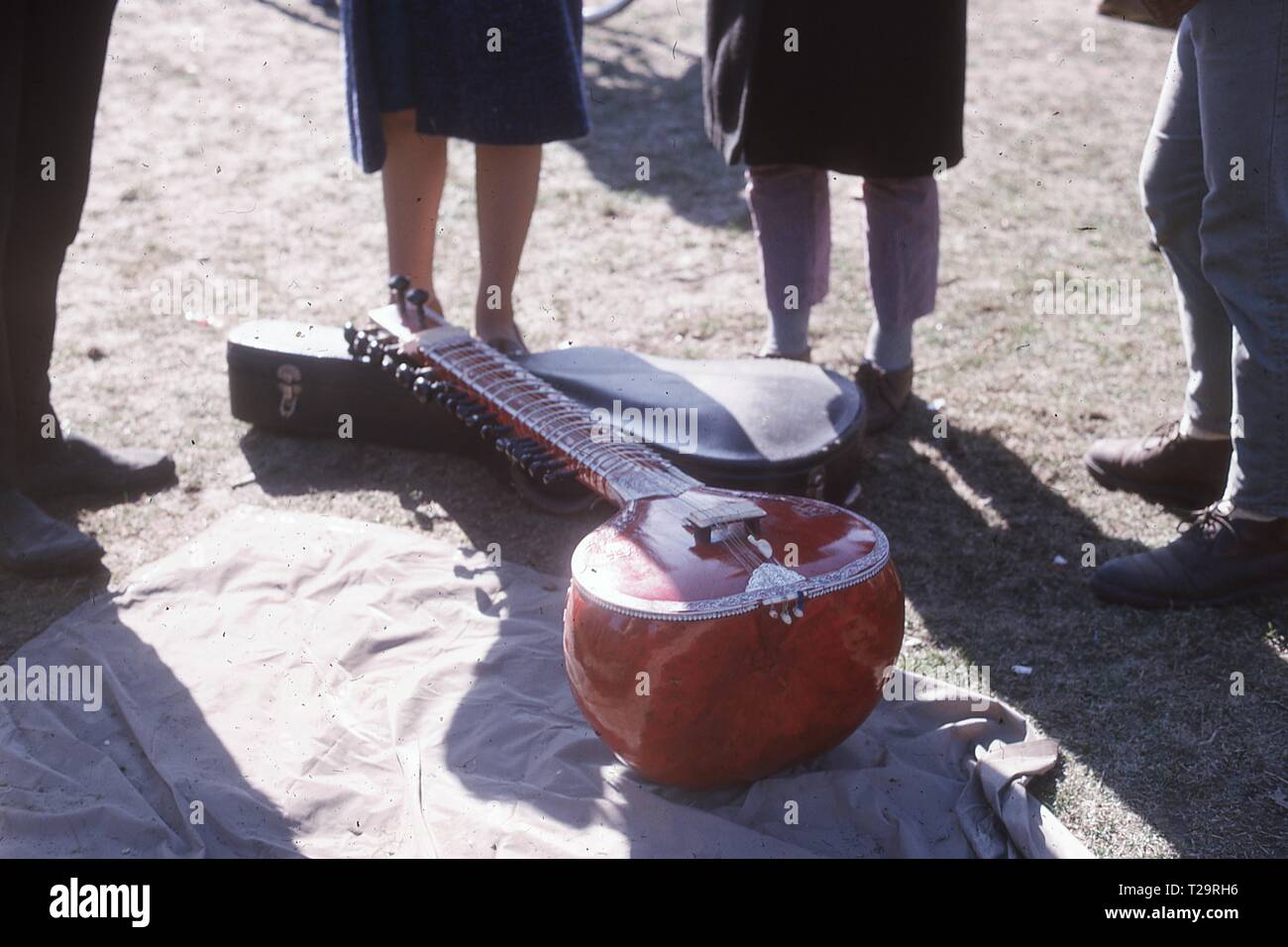 Nahaufnahme einer Sitar ruht auf einer Decke mit seinen Hals auf einer E-Gitarre, durch die Beine der Menschen die Teilnahme an den Central Park umgeben Be-In Proteste, New York City, März, 1967. () Stockfoto