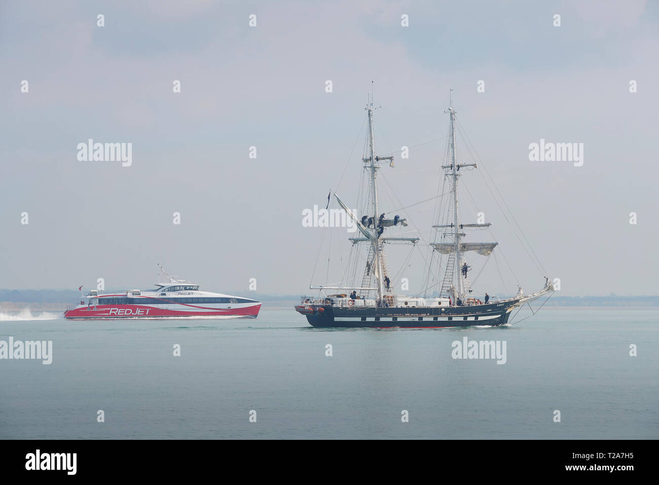 Die Ausbildung Schiff (Tall Ship), TS-ROYALISTISCHEN, Abfahrt im Hafen von Southampton, UK. Die Isle of Wight Fähre führt Hinter. 28. März 2019. Stockfoto