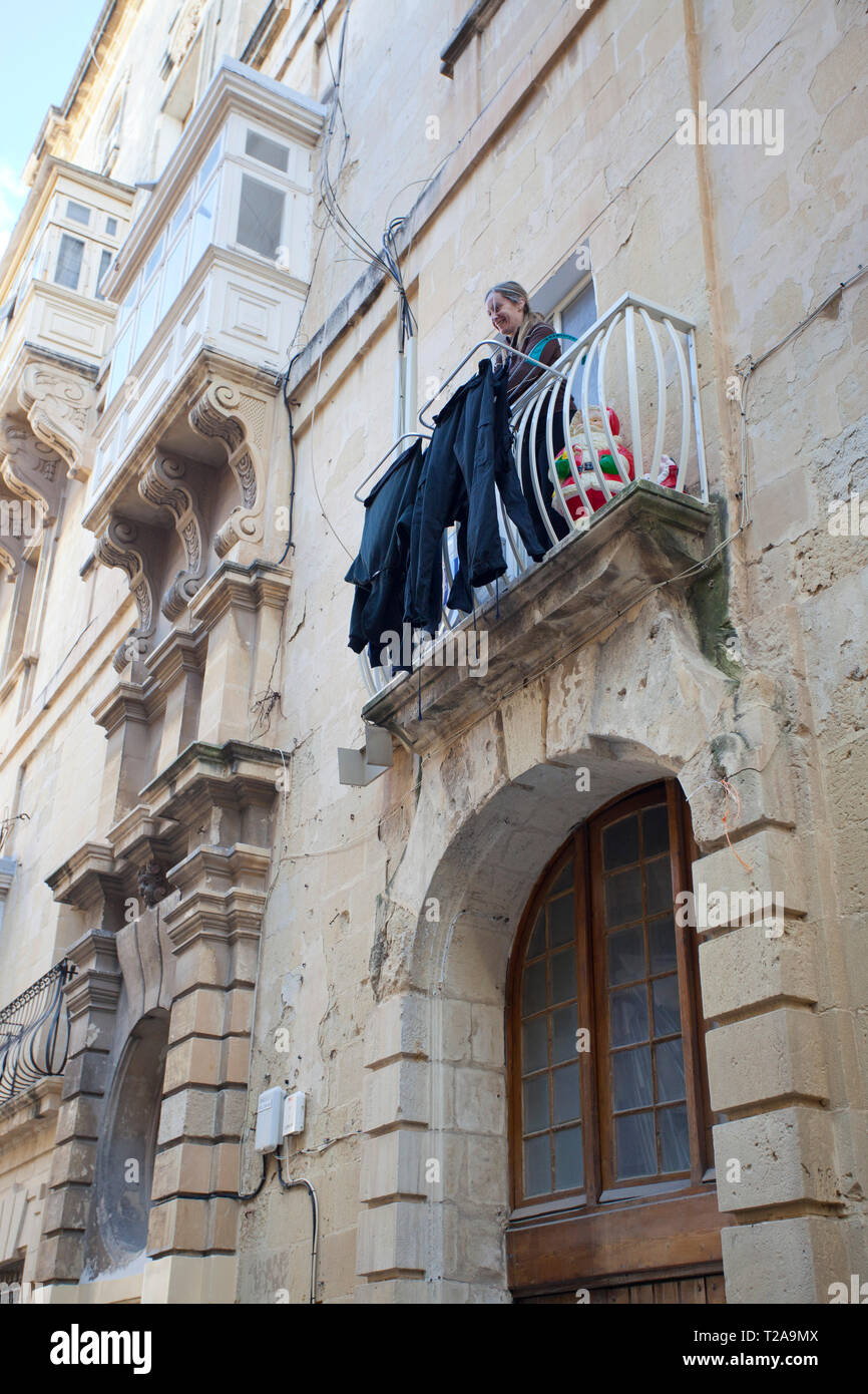 Frau trocknet Wäsche auf ihrem Balkon Stockfoto