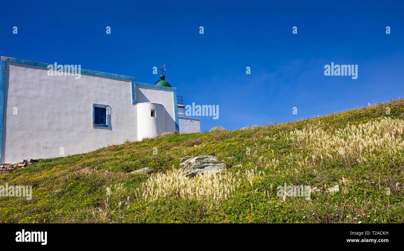 Griechenland. Kea Insel Leuchtturm. Weiße Farbe Gebäude, bunte Blumen auf grünem Gras, blau klar Himmel Hintergrund Stockfoto