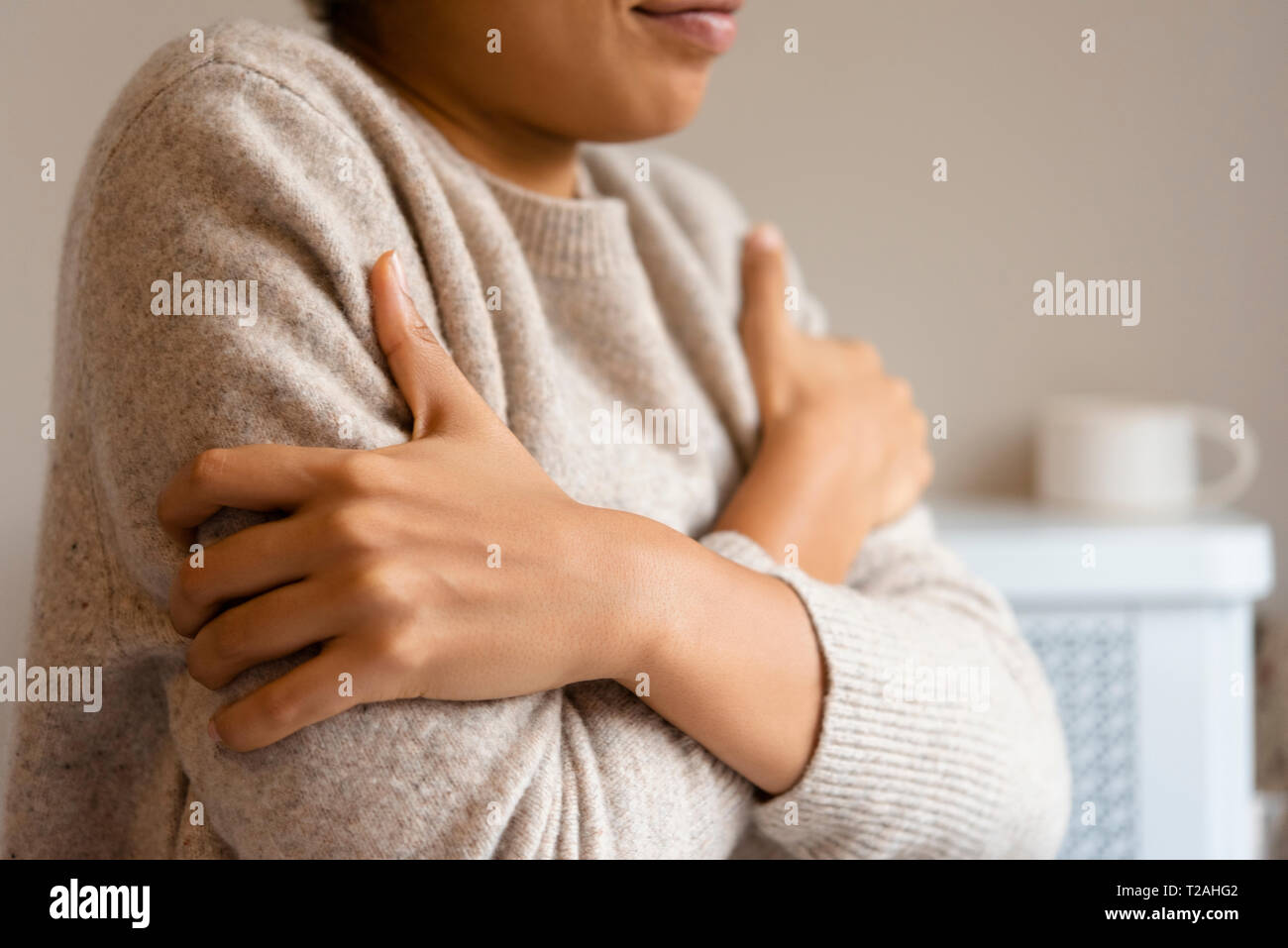 Gekreuzte Arme der Frau in Pullover Stockfoto