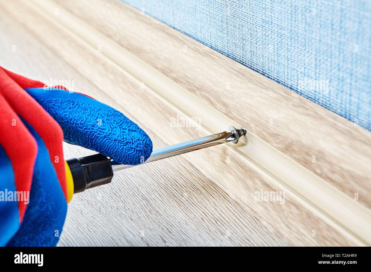 Anziehen der Schraube in flexiblen Sockel für den Fußboden mit Werkzeug  Hand durch Elektriker, close-up Stockfotografie - Alamy