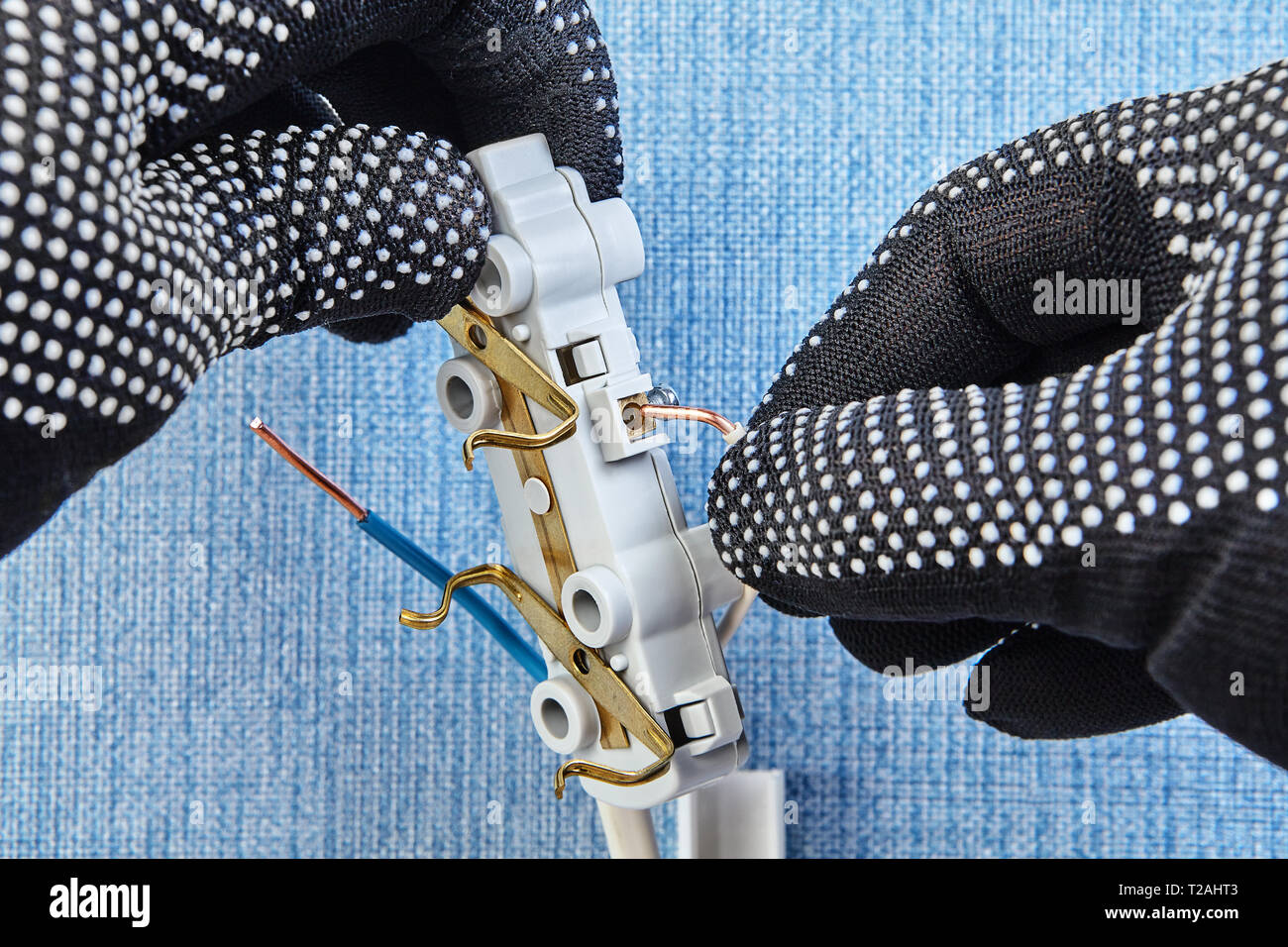 Arbeiter in Schutzhandschuhe wird die neue elektrische Stecker. Stockfoto