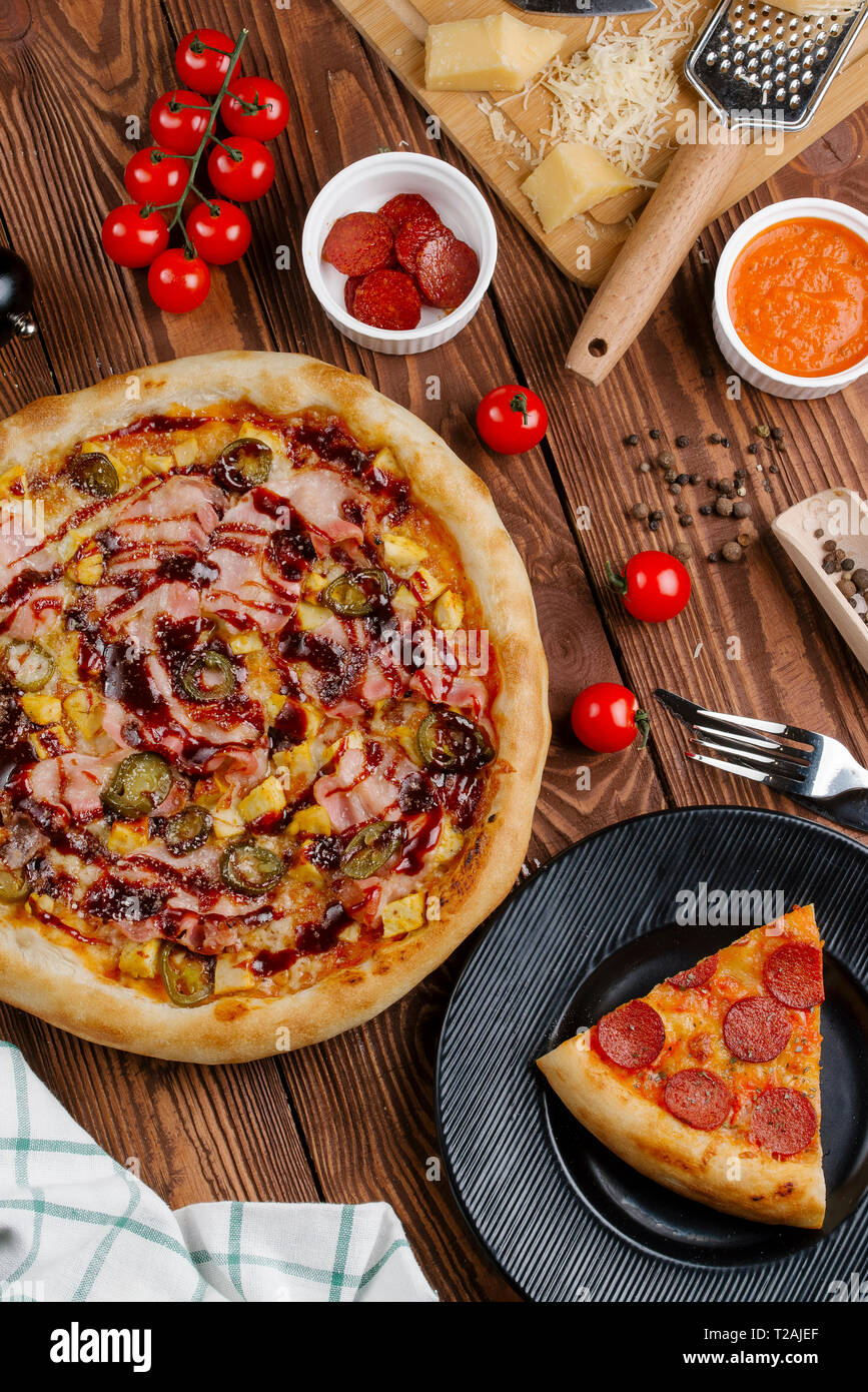 Pizza und Zutaten auf hölzernen Tisch Stockfoto