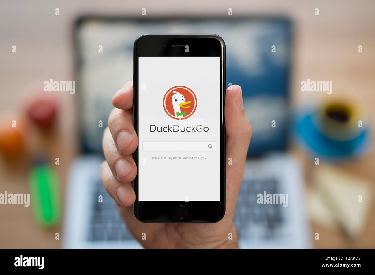 Ein Mann schaut auf seinem iPhone die zeigt die DuckDuckGo Logo (nur redaktionelle Nutzung). Stockfoto
