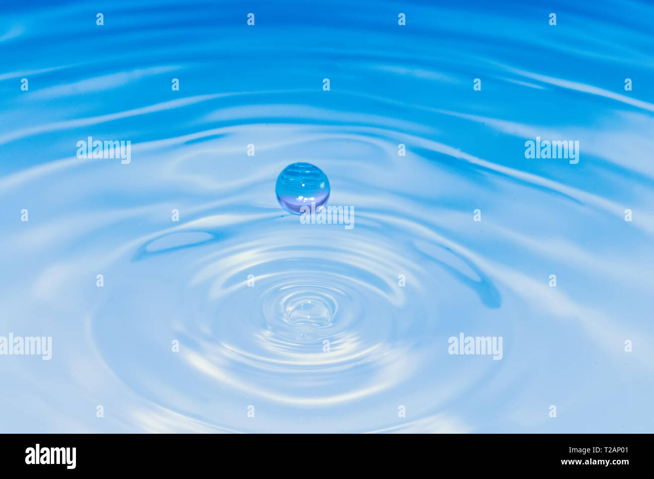 Hellblau gefärbte Wasser Tropfen Splash und Kräuselungen. Makroaufnahme Stockfoto