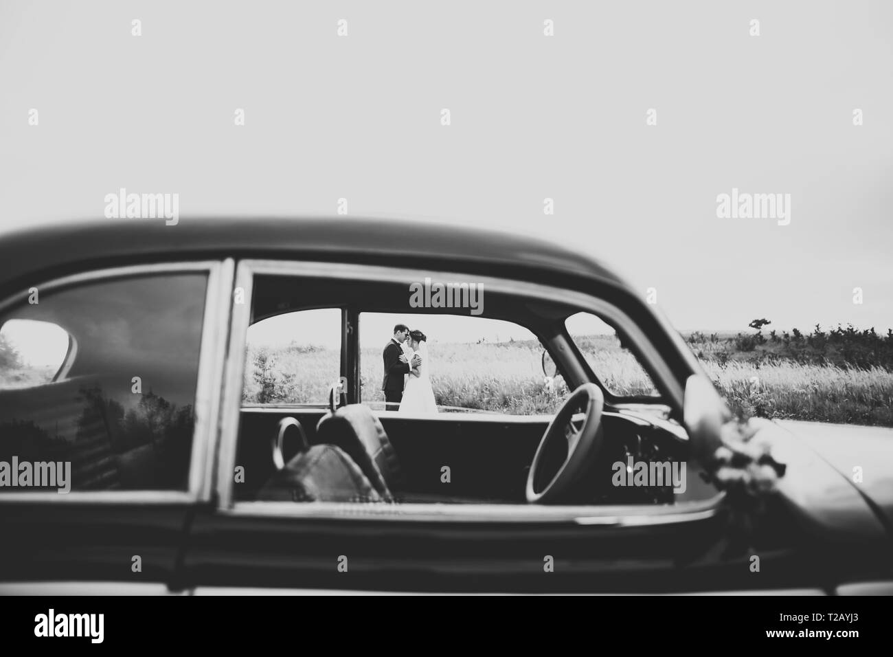 Happy jungvermählte Paar, Mann und Frau Küssen in der Nähe von eleganten retro Auto. Stockfoto